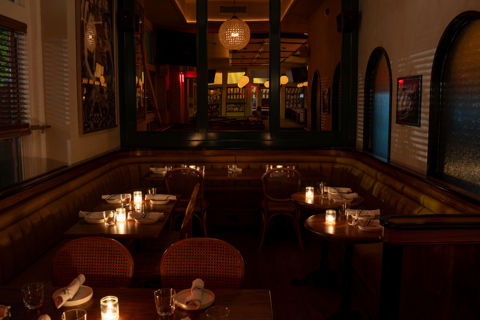 Georgie's Corner — a curved leather banquette with candlelit round tables beneath a crystal chandelier.